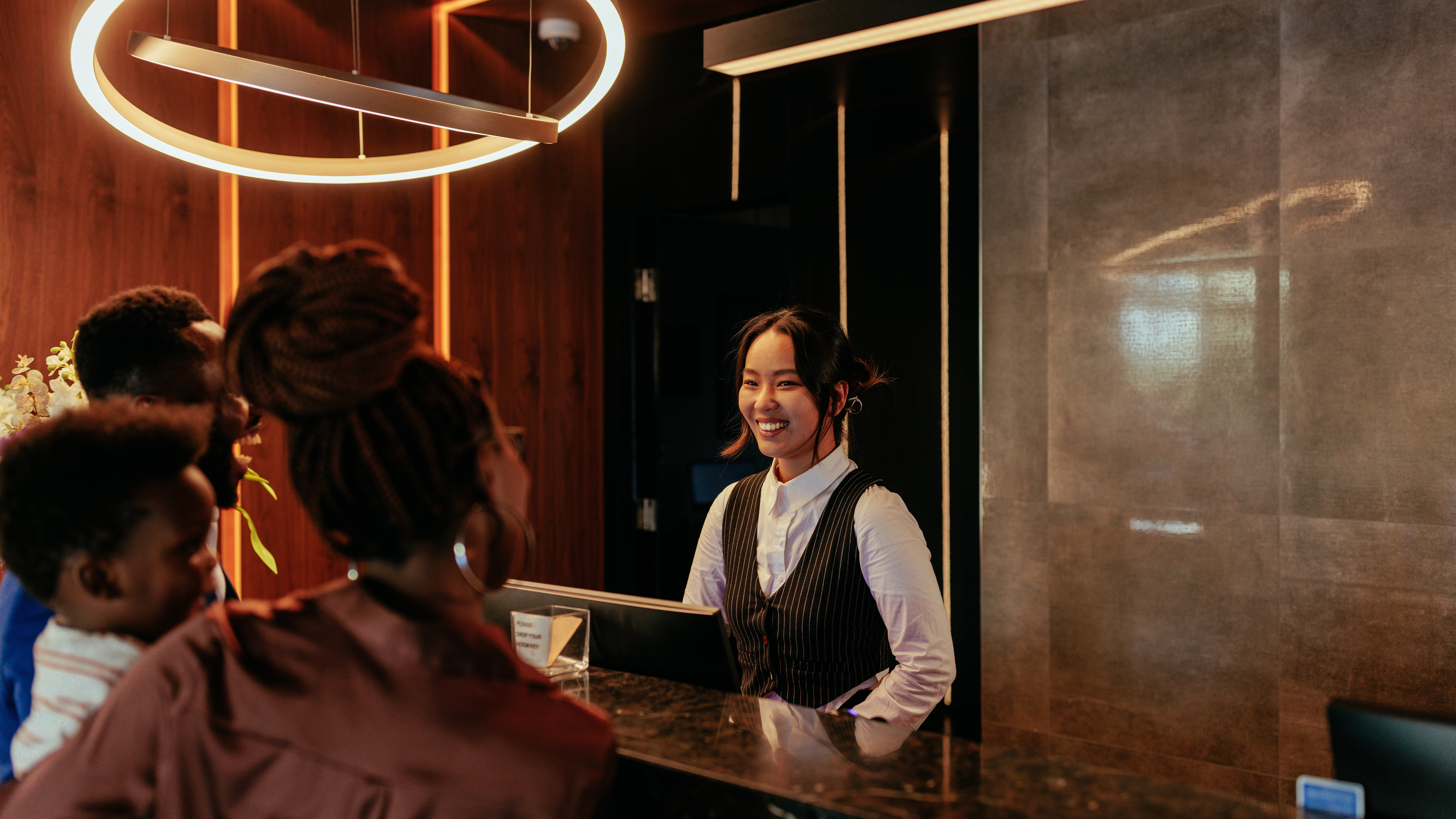 Eine lächelnde Rezeptionistin, die mit Hotelgästen spricht