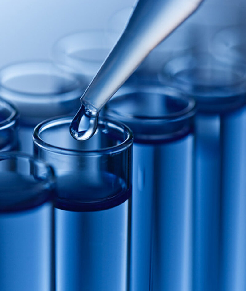 Mehrere Reagenzgläser, in ein Reagenzglas wird mit einer Pipette eine Flüssigkeit gegeben. 