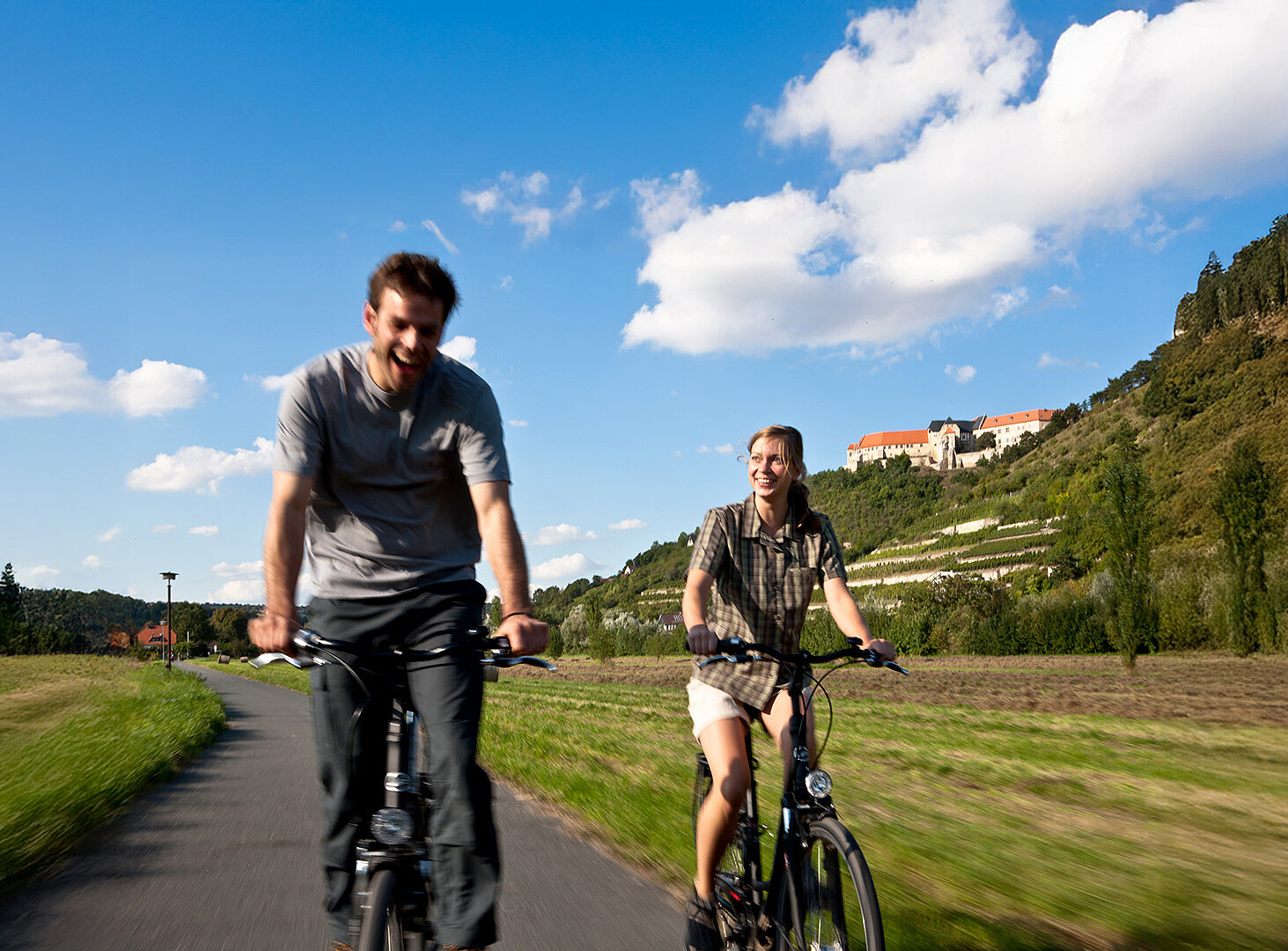 Zwei Personen fahren mit dem Fahrrad durch eine Landschaft.