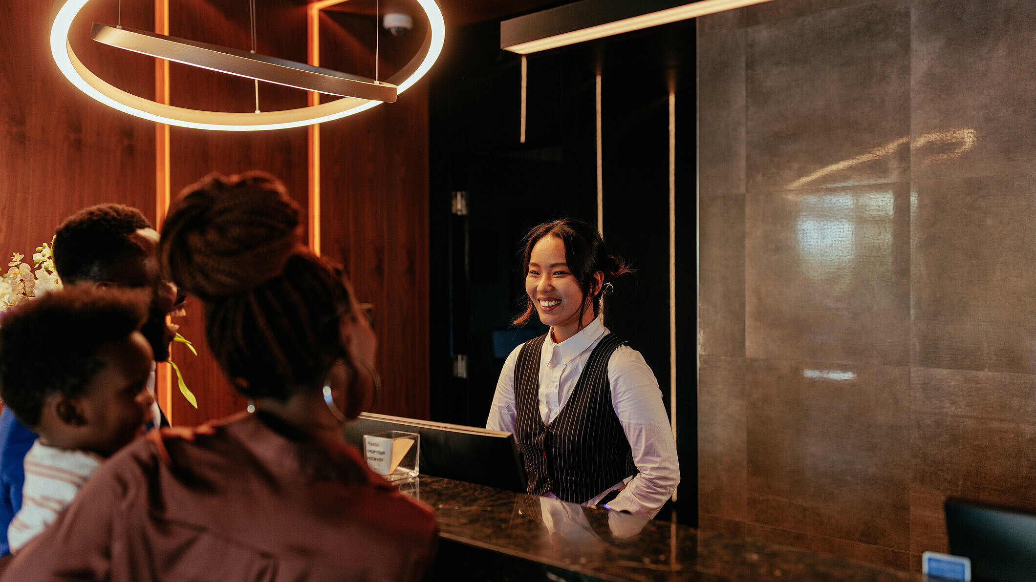 Eine lächelnde Rezeptionistin, die mit Hotelgästen spricht
