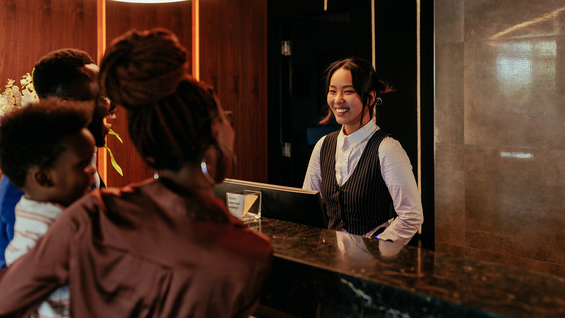 Eine lächelnde Rezeptionistin, die mit Hotelgästen spricht