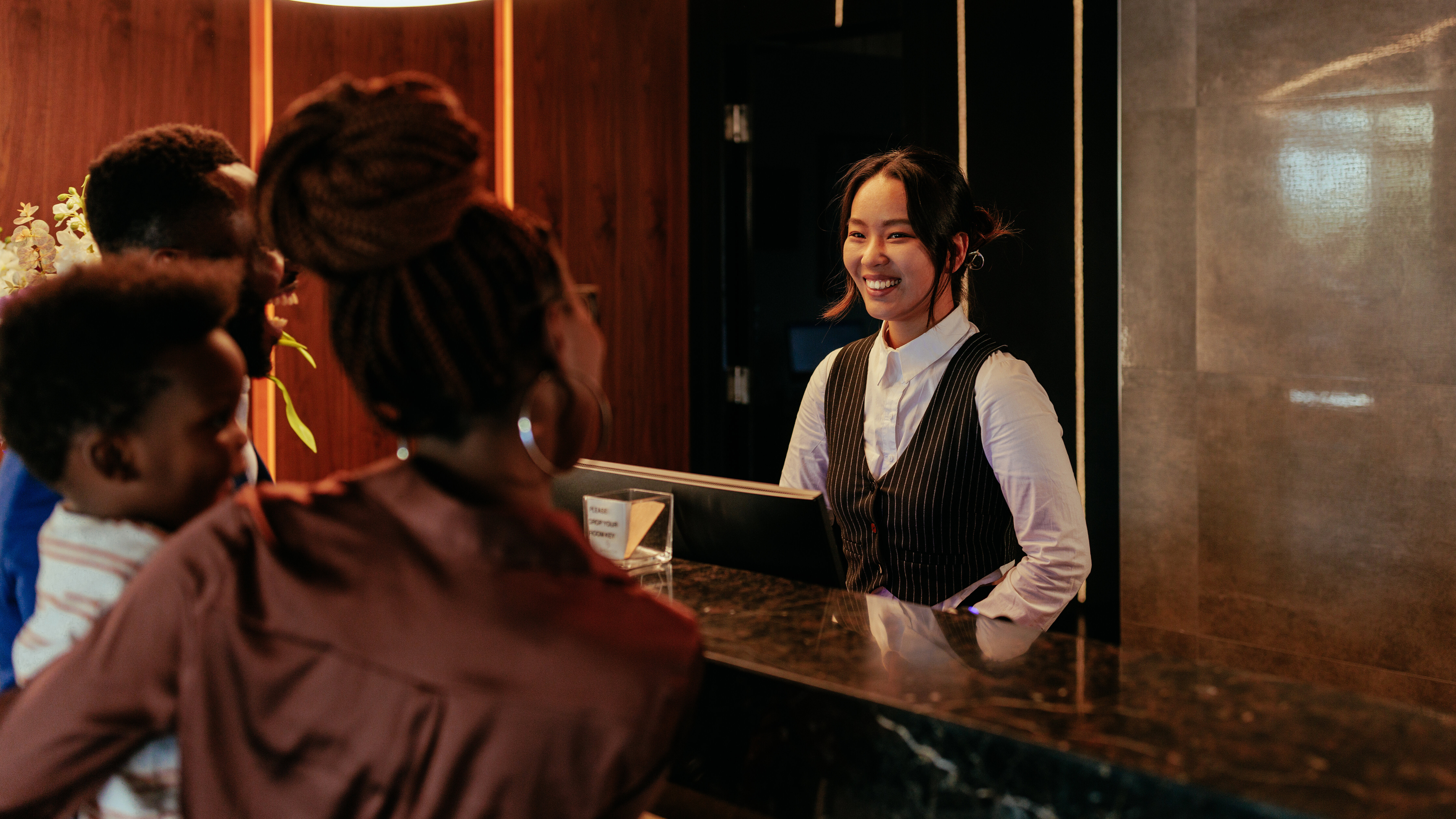 Eine lächelnde Rezeptionistin, die mit Hotelgästen spricht