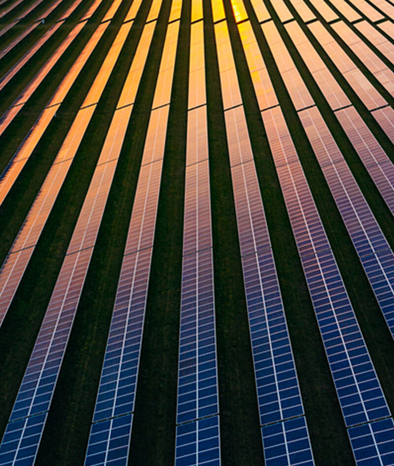 Drohnenansicht eines Solarmodulfeldes bei Sonnenuntergang