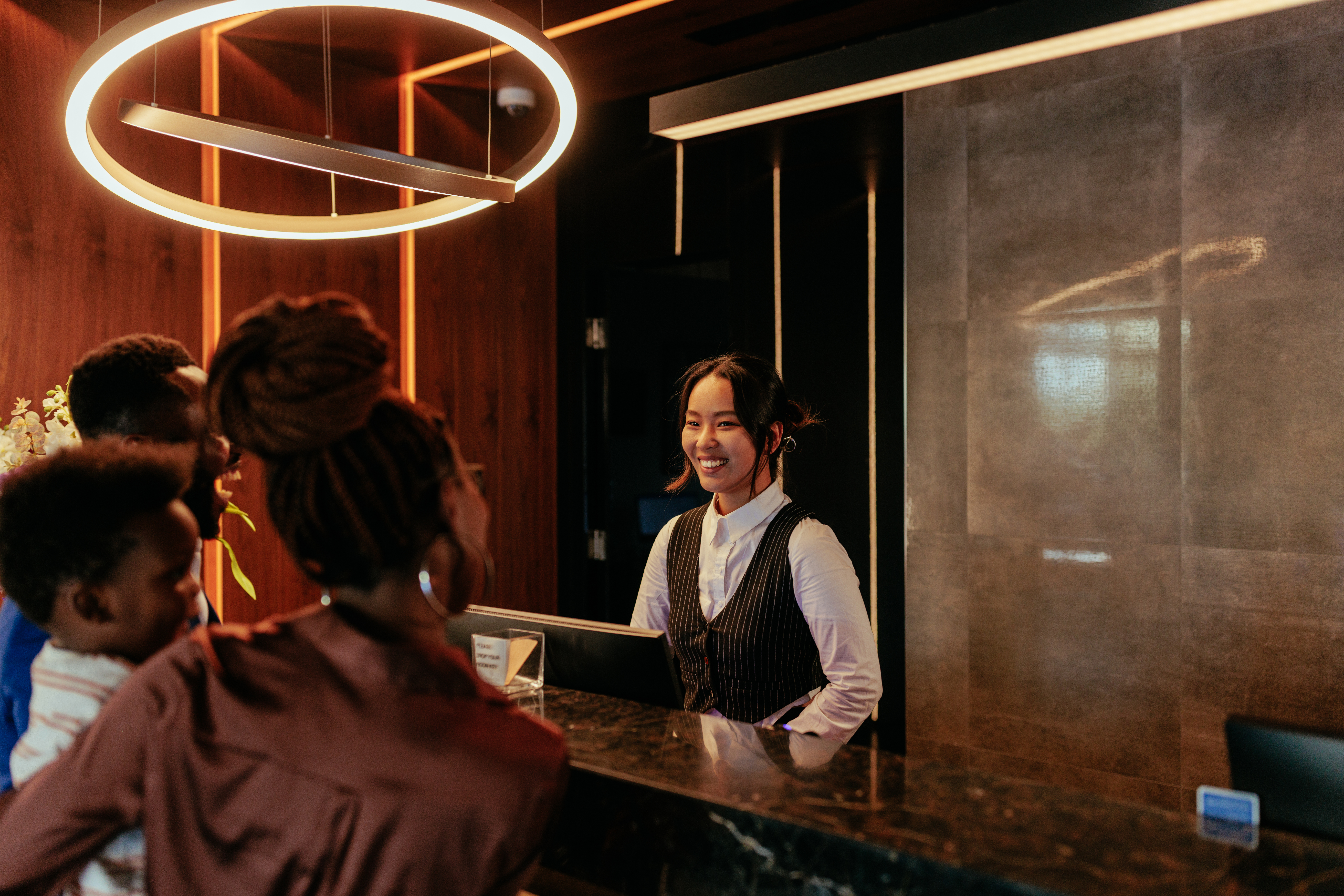 Eine lächelnde Rezeptionistin, die mit Hotelgästen spricht